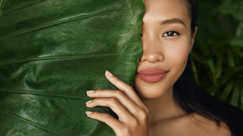 Woman posing behind a leaf