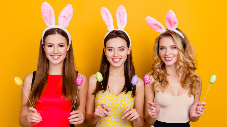 Three happy women wearing Easter bunny ears and eggs