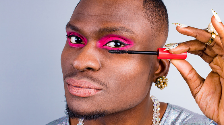 Person wearing pink eyeshadow applying mascara