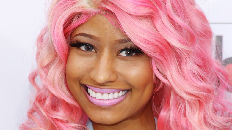 Closeup of Nicki Minaj smiling with pink hair on step-and-repeat