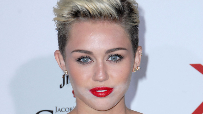 Closeup of Miley Cyrus smiling on step-and-repeat with white powder around her mouth
