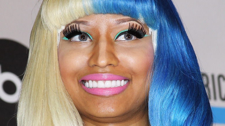 Closeup of Nicki Minaj smiling on step-and-repeat in blue and blond wig