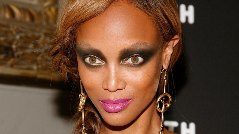 Closeup of Tyra Banks with harsh, dark eye makeup and bright pink lips