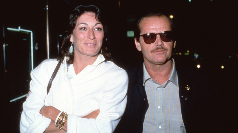 Smiling Anjelica Huston in a white coat beside Jack Nicholson