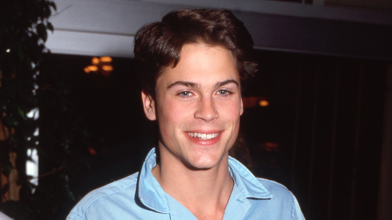Young Rob Lowe smiling in a baby blue shirt