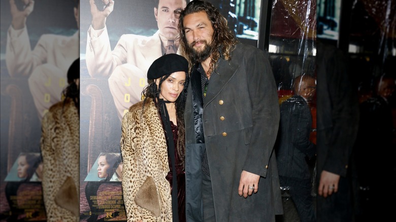 Jason Momoa wearing a gray coat and Lisa Bonet in animal print while attending a movie premiere.