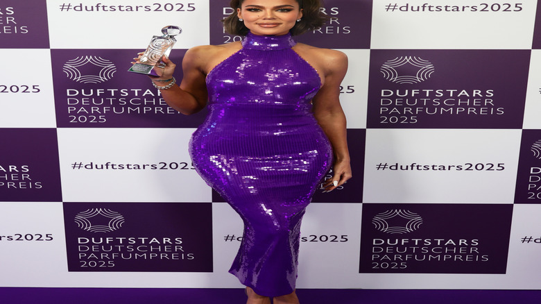 Khloé Kardashian in a purple sequin dress holding an award