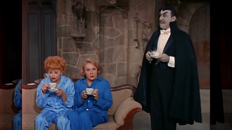 Lucille Ball and Vivian Vance drinking from teacups next to Shepherd Sanders dressed as Dracula next to