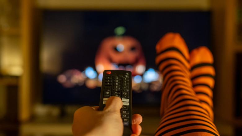 Remote control pointed toward pumpkin on TV