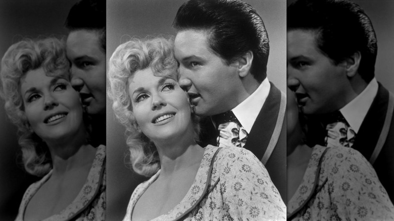 Elvis Presley standing behind Donna Douglas with his lips pressed against her cheek