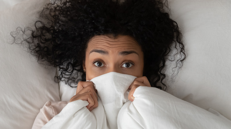 Woman hiding under bed sheet