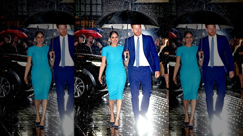 Meghan Markle and Prince Harry walking under umbrella in the rain