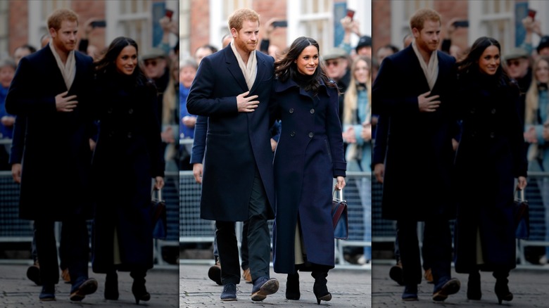 Prince Harry and Meghan Markle smiling and walking past crowd behind barriers in Nottingham