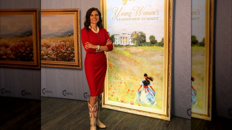 Nancy Mace with her arms crossed over her chest in front of a painted sign.