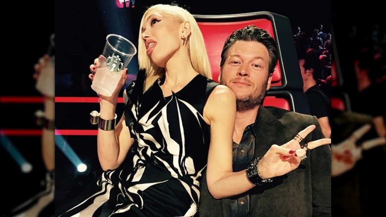 Gwen Stefani holding a Starbucks cup and sitting on Blake Shelton's lap on the set of "The Voice"