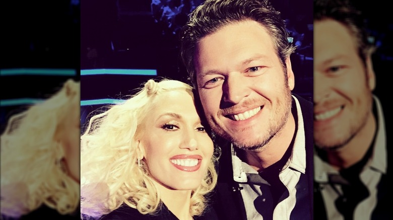 Gwen Stefani and Blake Shelton smiling in a selfie taken on "The Voice" set