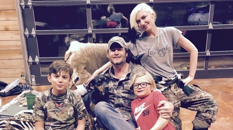 Gwen Stefani, Blake Shelton, Kingston Rossdale, and Zuma Rossdale sitting on a chair with a deer fur on the back