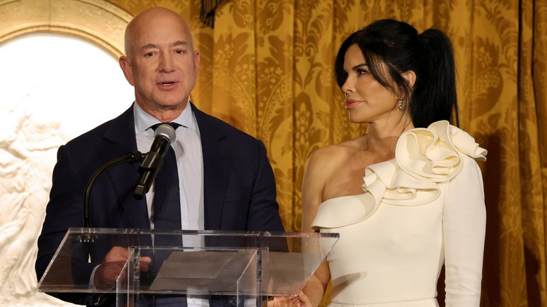 Jeff Bezos and Lauren Sánchez standing at a podium in 2023