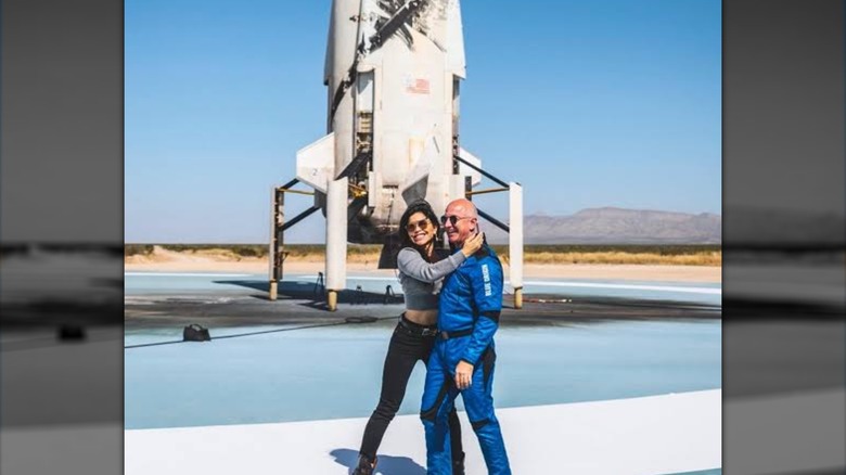 Lauren Sánchez and Jeff Bezos posing together in front of a Blue Origin rocket.
