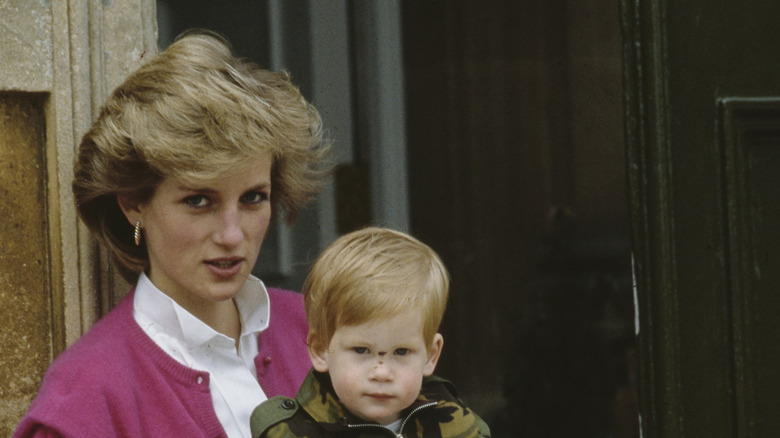 Princess Diana in a pink sweater holding baby Prince Harry