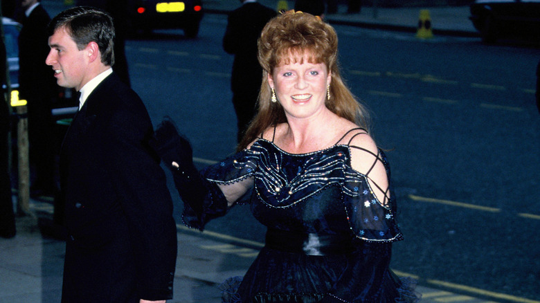 Prince Andrew walking ahead of a waving Sarah Ferguson at event