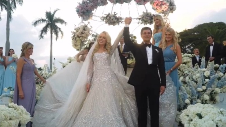 Tiffany Trump and Michael Boulos holding hands up in the air at the altar on their wedding day