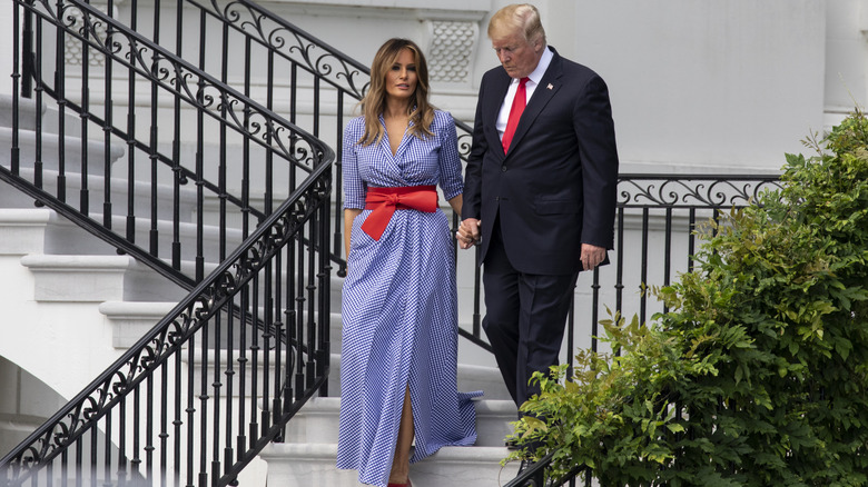 President Trump and the First Lady walk down the stairs of the White House for an Independence Day event on 2018