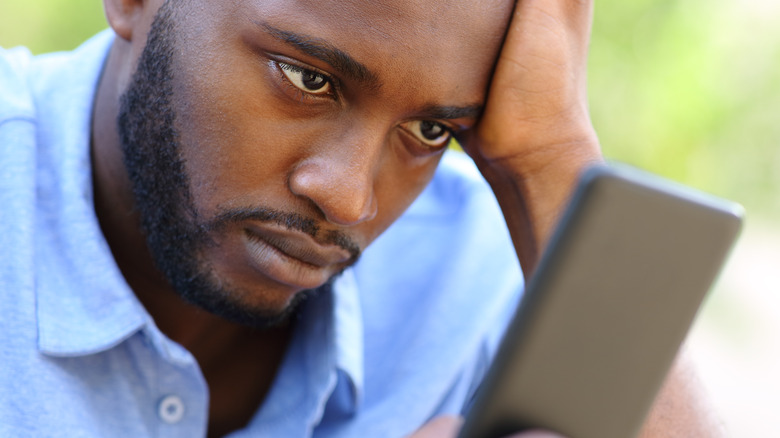 Man wearily looking at phone