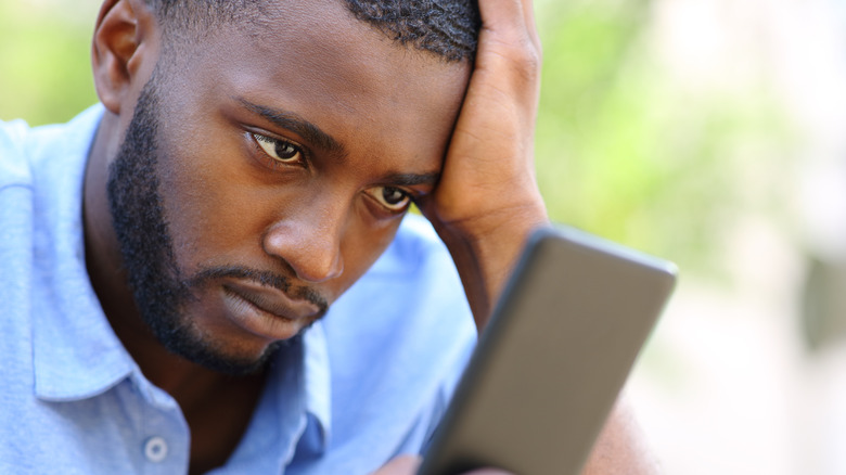 Man wearily looking at phone