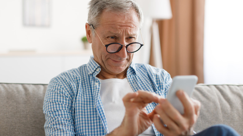 Man wearing glasses texting on couch