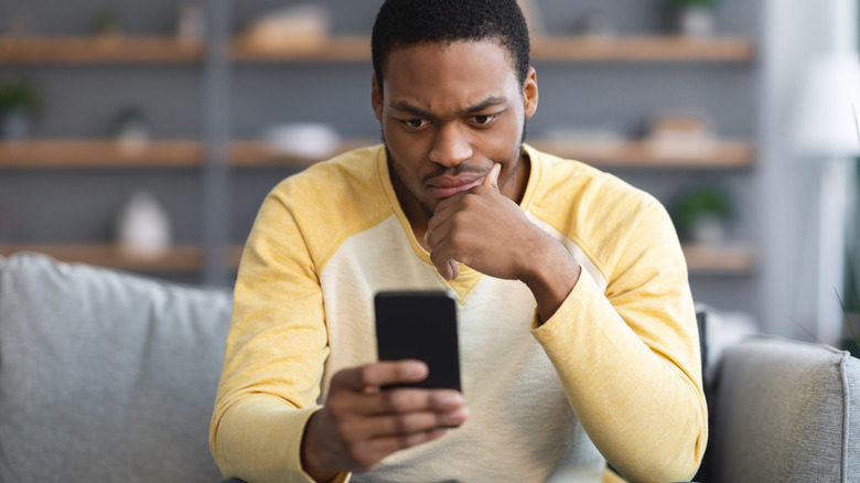 Man on couch stares at phone