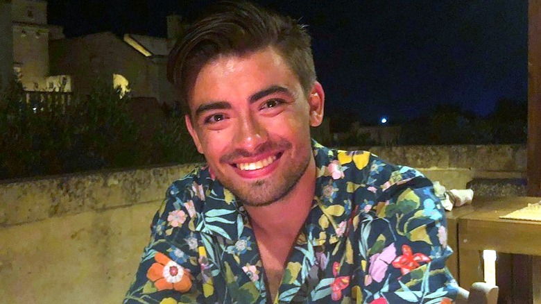 Kelly Ripa's first-born child Michael Consuelos smiling and wearing a floral shirt