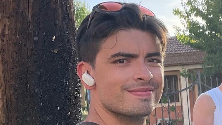 Kelly Ripa's oldest son Michael Consuelos smiling with earbuds with sunglasses on his head