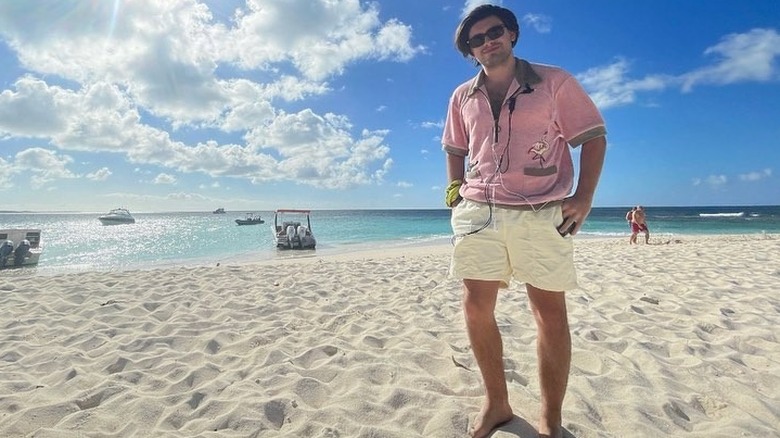 Michael Consuelos smiling on a beach while wearing a producer's headset around his neck