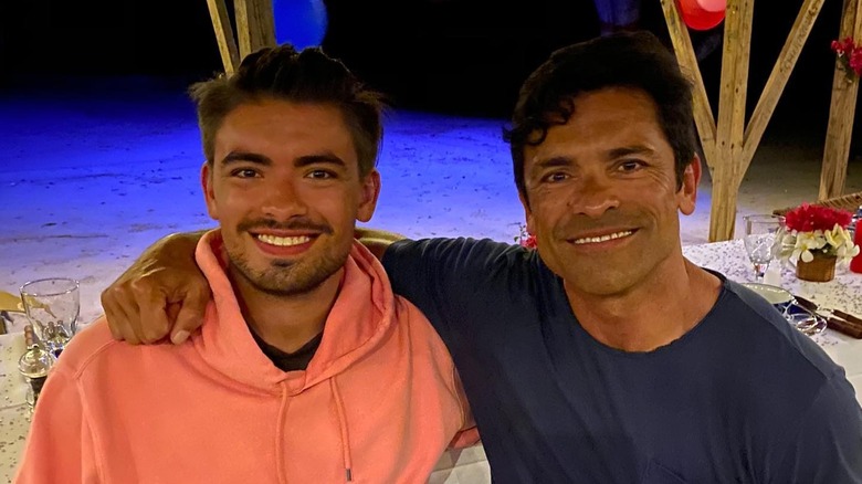 Mark Consuelos with his arm around his son, Michael Consuelos, on a beach.