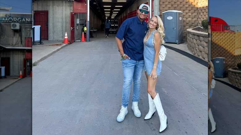 Patrick Mahomes and Brittany Mahomes posing together in a parking lot.