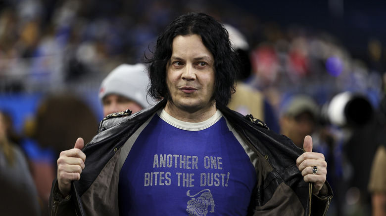 Jack White opening his leather jacket to reveal a Detroit Lions T-shirt at an NFL game
