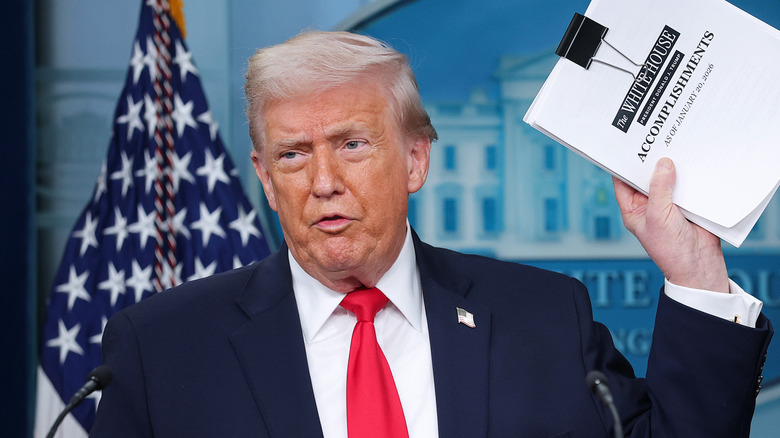 Donald Trump holding up a sheath of papers with the title 
