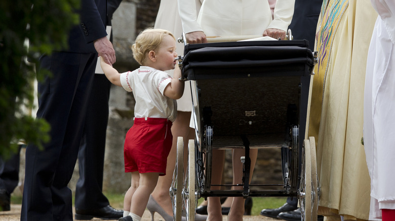 Prince George leans over sister Princess Charlotte's stroller