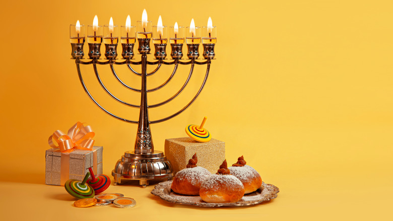 Hanukkah menorah lit with treats and gifts
