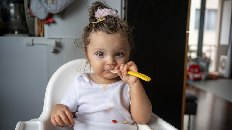 A baby girl with a small fork in her mouth