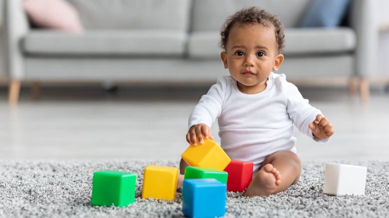 A baby boy playing with square blocks