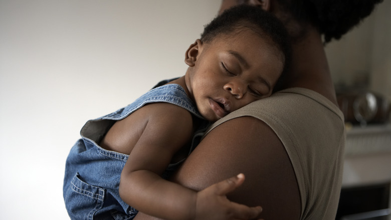 A baby sleeping in a woman's arms