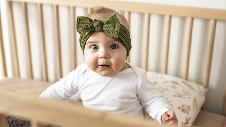 A baby girl sitting in a crib