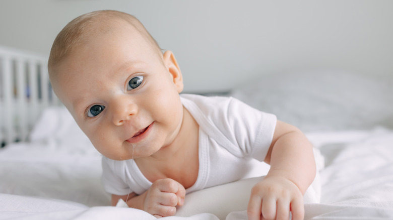 A baby boy on his stomach dressed in white