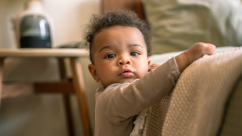 A baby boy looking forward, over his shoulder