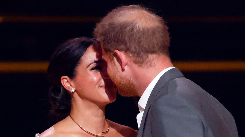 Meghan Markle and Prince Harry kissing on stage at the 2022 Invictus Games
