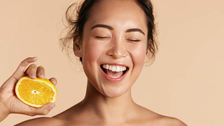 Woman smiling while holding orange