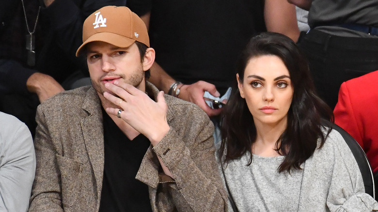 Ashton Kutcher and Mila Kunis sitting courtside