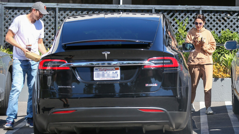 Ashton Kutcher and Mila Kunis entering their Tesla car in LA